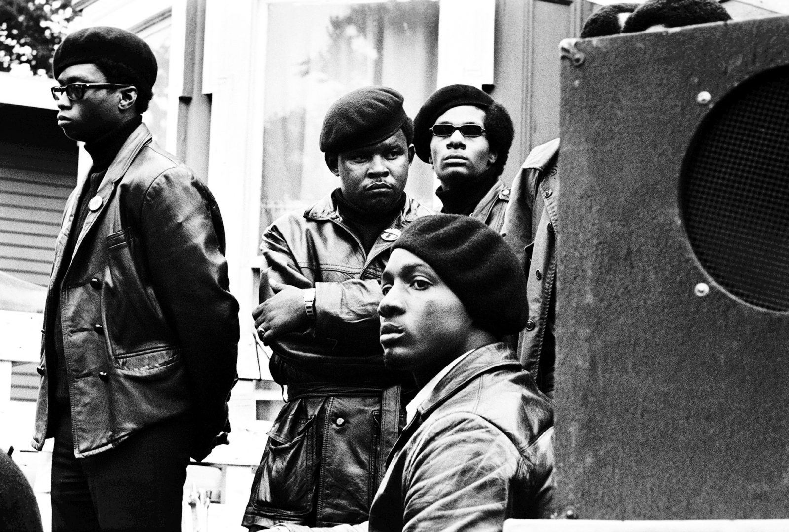 Panthers stand just off stage at a Free Huey rally in Defermery Park. Cle Brooks (arms folded). Cle was a San Francisco Panther who went to San Quentin Prison and started the San Quentin chapter of the BPP. 1968